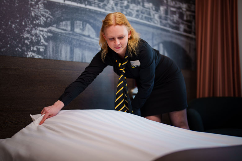 Housekeepingmedewerker maakt een hotelbed op